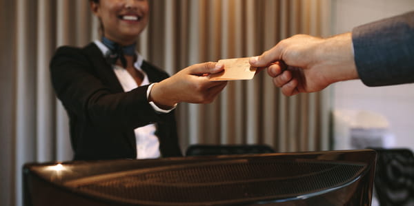  Close up of businessman paying with credit card at reception desk in hotel. Business man giving credit card to hotel receptionist for payment of his room. Focus on hands.