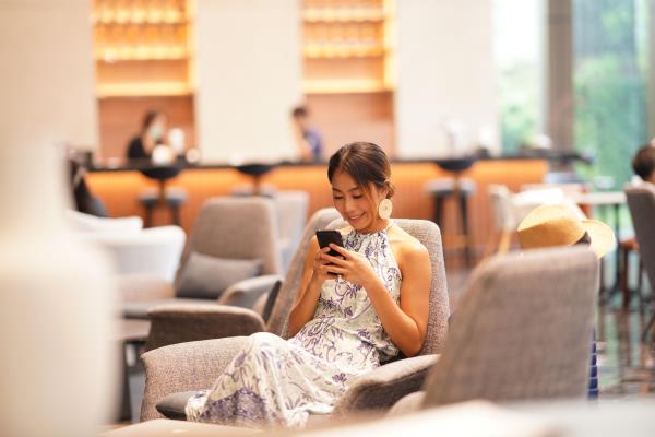 Woman sitting in airport lounge and using her phone