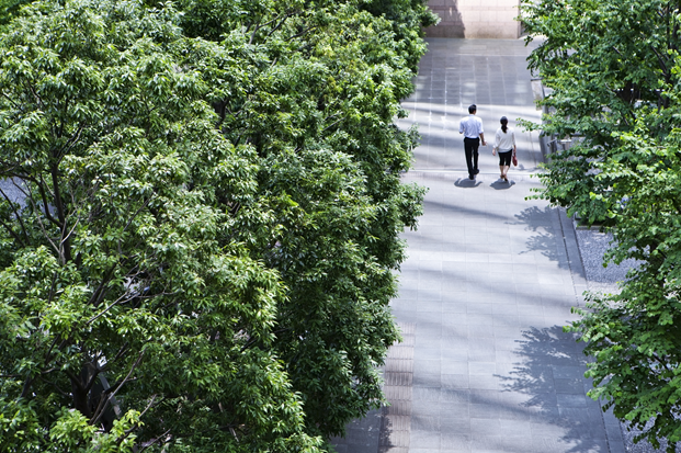 Two People walking down a road with Trees on either side